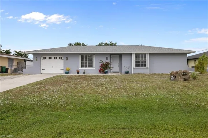 Ranch-style home with a front lawn, stucco siding, concrete driveway, and a garage