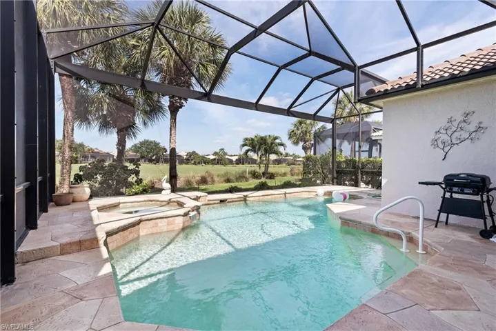 View of swimming pool featuring a patio area, glass enclosure, a pool with connected hot tub, and area for grilling