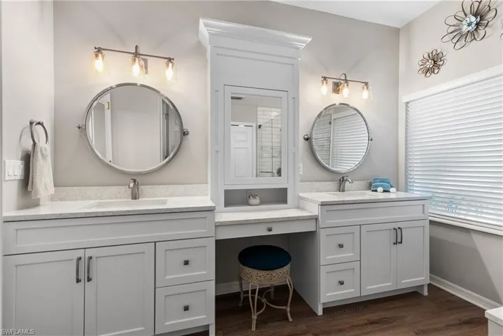 Bathroom featuring two vanities, wood finished floors, baseboards, and a sink