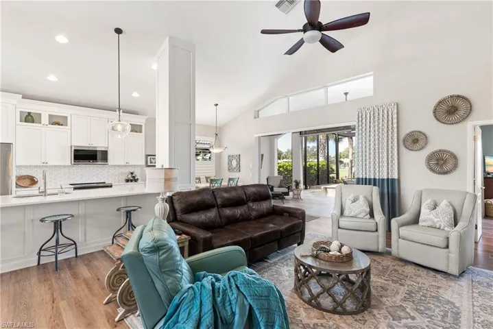 Living room with recessed lighting, visible vents, light wood-style floors, high vaulted ceiling, and ceiling fan