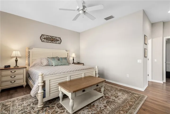 Bedroom with baseboards, a ceiling fan, wood finished floors, and visible vents
