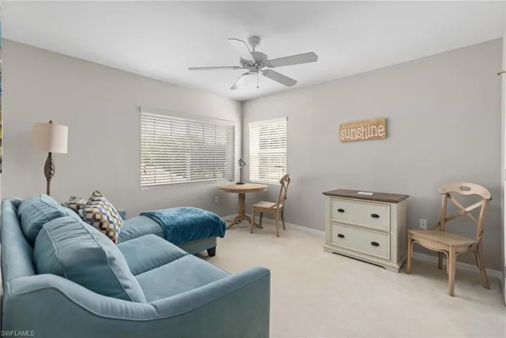 Living area featuring light carpet, a ceiling fan, and baseboards