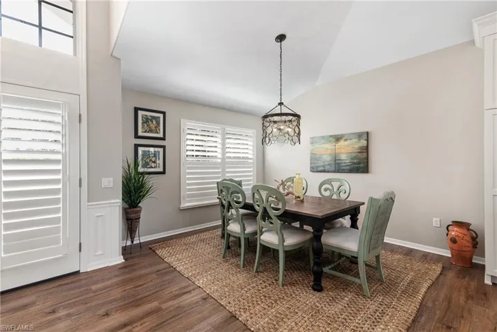 Dining room featuring baseboards, lofted ceiling, dark wood-style floors, and a notable chandelier