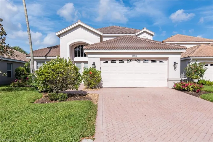Mediterranean / spanish house with a front lawn, a tiled roof, an attached garage, stucco siding, and decorative driveway