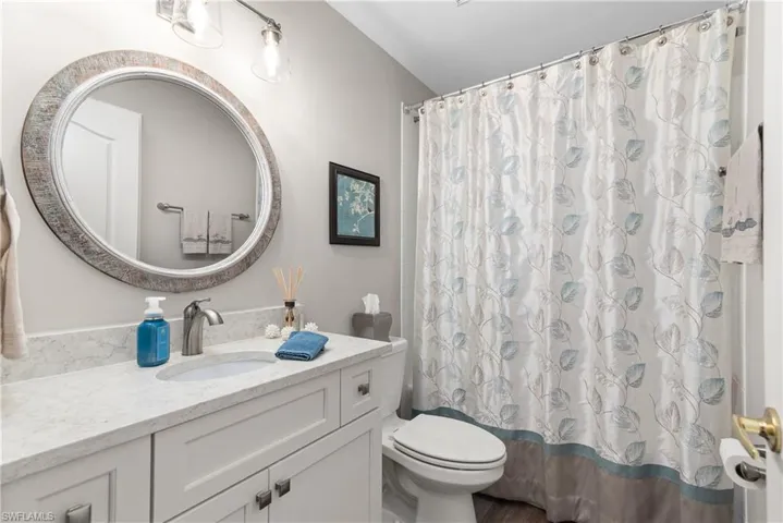 Bathroom with toilet, a shower with curtain, and vanity