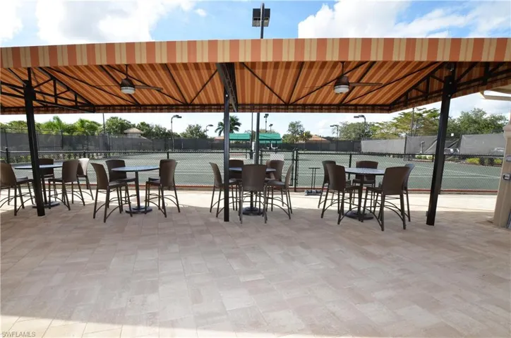 View of patio featuring a tennis court, fence, and ceiling fan