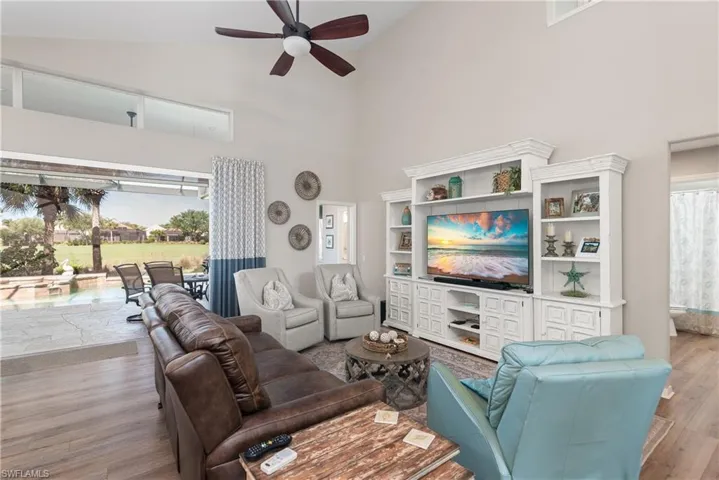 Living area with wood finished floors, high vaulted ceiling, and ceiling fan