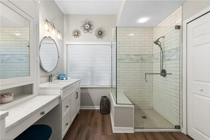Full bathroom with baseboards, vanity, wood finished floors, and a stall shower