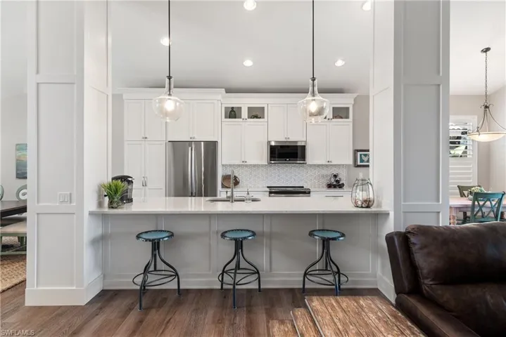 Kitchen with glass insert cabinets, a peninsula, stainless steel appliances, and a sink