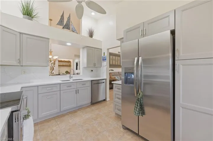 Kitchen featuring stainless steel appliances, a high ceiling, a ceiling fan, backsplash, and gray cabinetry