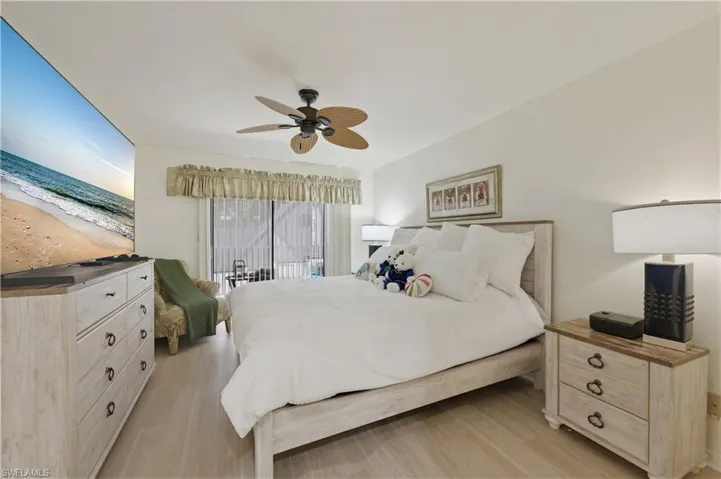 Bedroom with access to exterior, light wood-style floors, and a ceiling fan