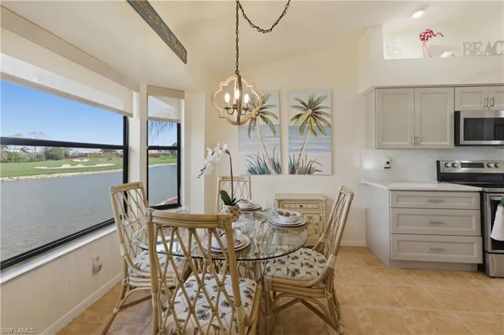Dining area featuring lofted ceiling, a water view, hanging lights, and light tile patterned flooring