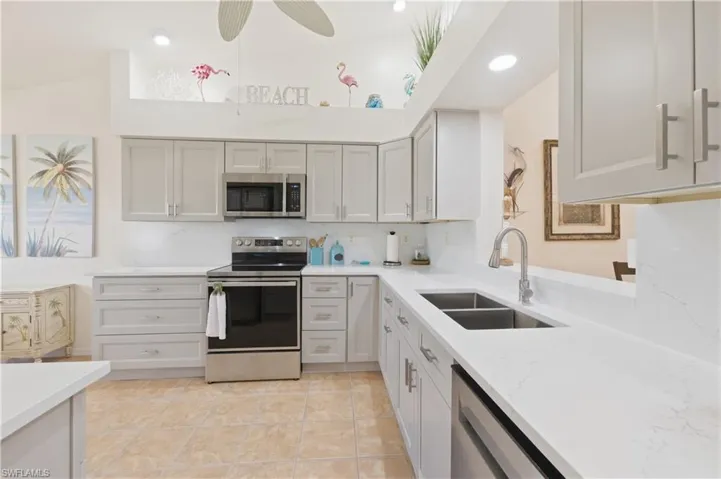 Kitchen with stainless steel appliances, light stone countertops, backsplash, lofted ceiling, and ceiling fan