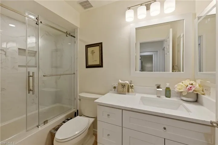 Bathroom featuring vanity and combined bath / shower with glass door