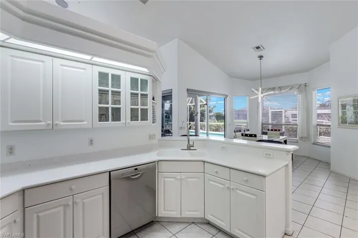 White kitchen featuring shaker-style cabinetry, a built-in dishwasher, and a corner sink