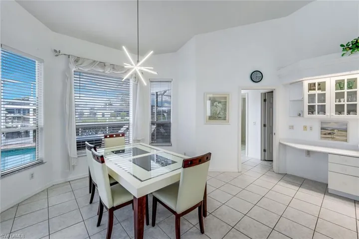 Dining area featuring a modern chandelier, bay windows with horizontal blinds, and tile flooring