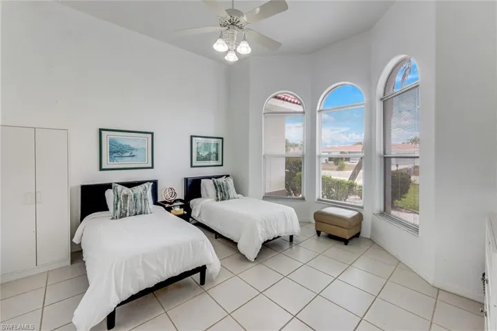 Room featuring vaulted ceilings with a ceiling fan, arched windows, and white tile flooring