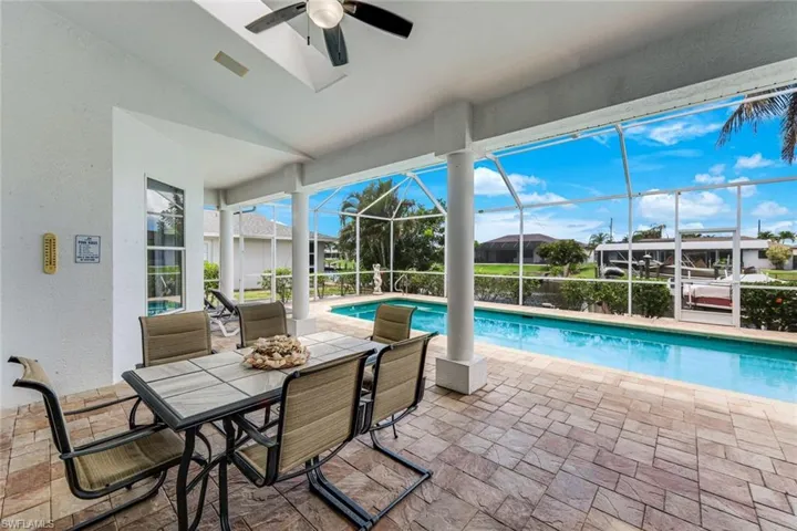 Screened patio with a paver-stone surface, a built-in ceiling fan, and an integrated swimming pool