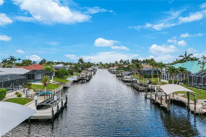 Waterfront property featuring extensive canal frontage, private boat docks, covered boat lifts, screened-in pools, and mature palm trees