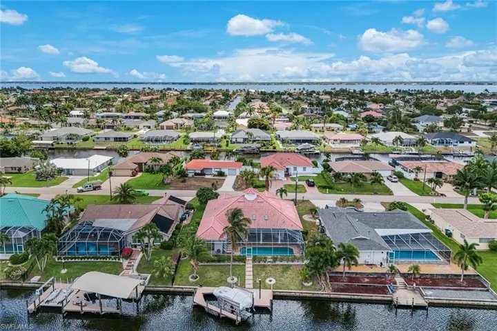 Waterfront neighborhood featuring canal access, private boat docks, screened pool enclosures, and mature palm trees