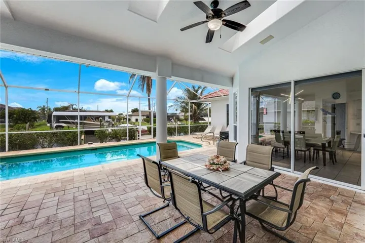 Screened lanai featuring a swimming pool, textured paver decking, and a ceiling fan