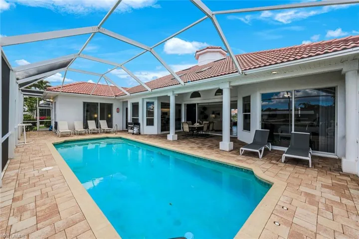 Screened swimming pool with a paved patio, red tile roof, and multiple sliding glass doors