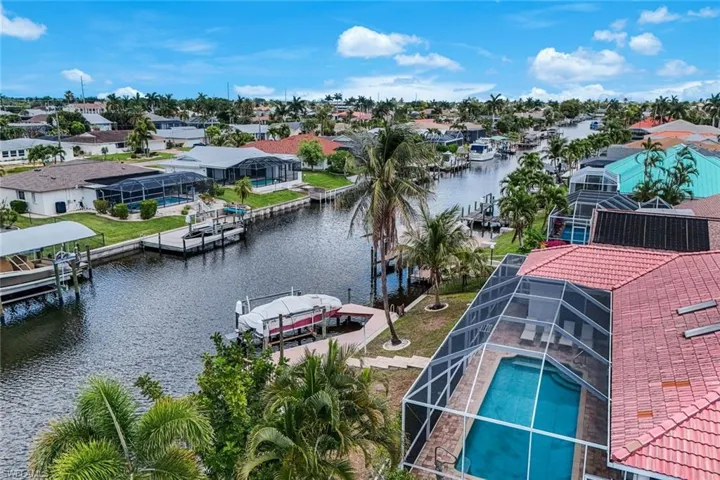 Residential property featuring a screened-in swimming pool and direct canal frontage