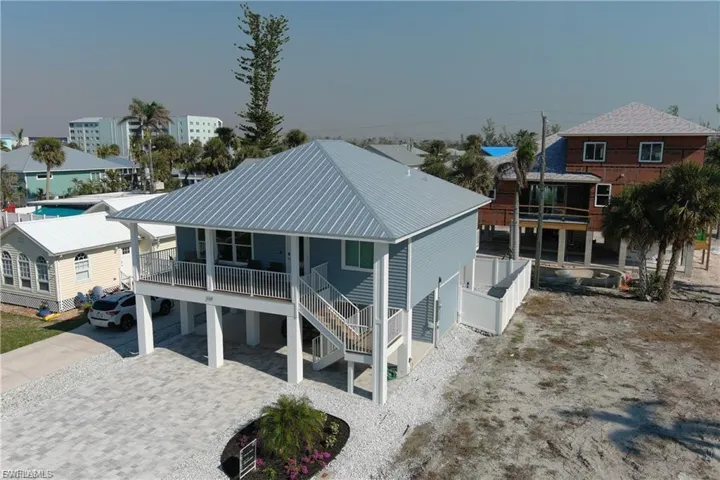 Rear view of property with a carport, driveway, a patio area, stairway, and a metal roof