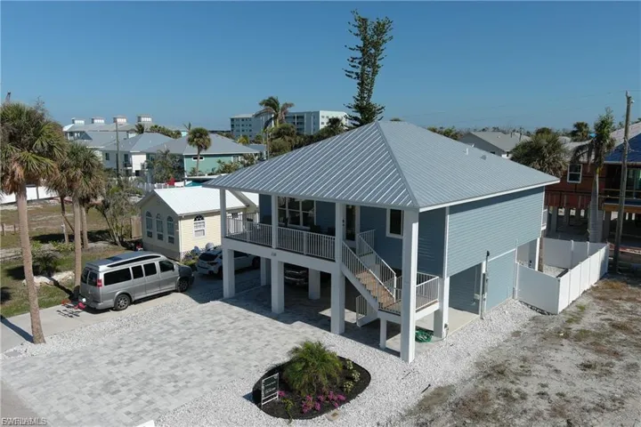 Back of house featuring a carport, stairway, a metal roof, and driveway