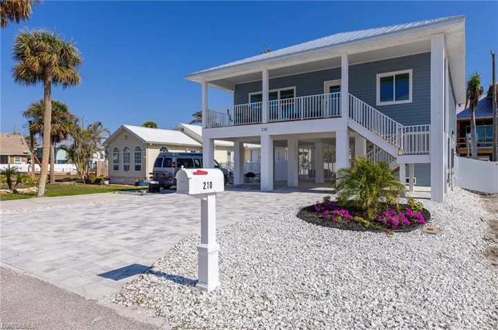 View of front of property featuring a carport, decorative driveway, a metal roof, stairway, and covered porch