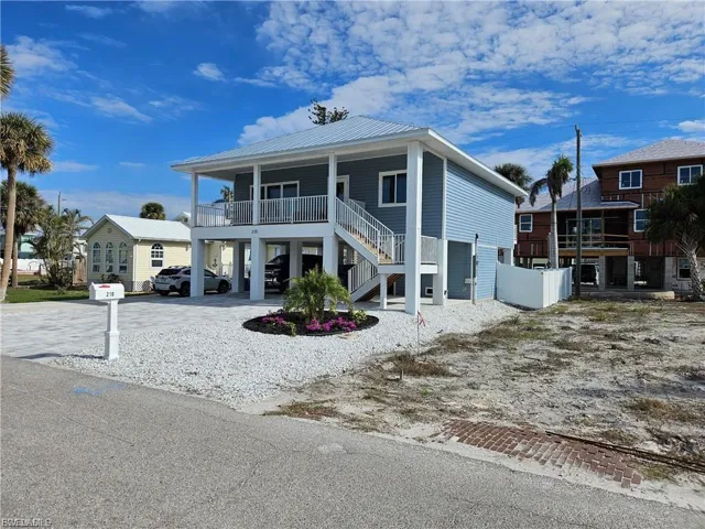 Raised beach house with stairway, a metal roof, a carport, and driveway