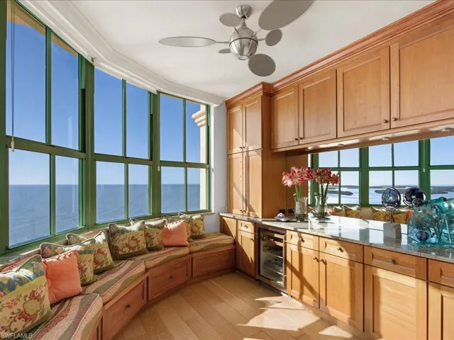 Kitchen featuring a water view, light wood-type flooring, ceiling fan, beverage cooler, and light stone countertops