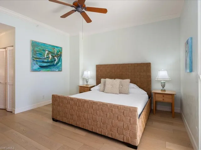 Bedroom featuring ceiling fan, ornamental molding, and light wood-type flooring