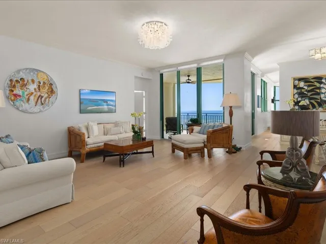 Living room with expansive windows, ornamental molding, light wood-type flooring, and a notable chandelier