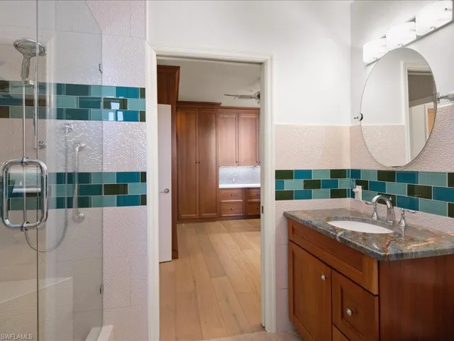 Bathroom with tasteful backsplash, vanity, an enclosed shower, and hardwood / wood-style flooring