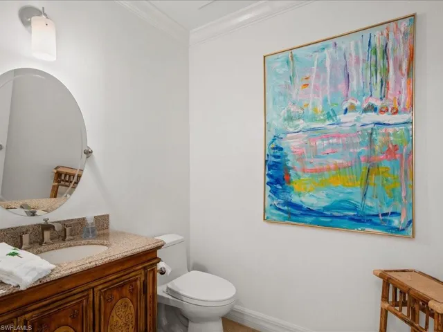 Bathroom with ornamental molding, vanity, and toilet