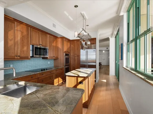 Kitchen featuring appliances with stainless steel finishes, decorative light fixtures, a center island, and sink