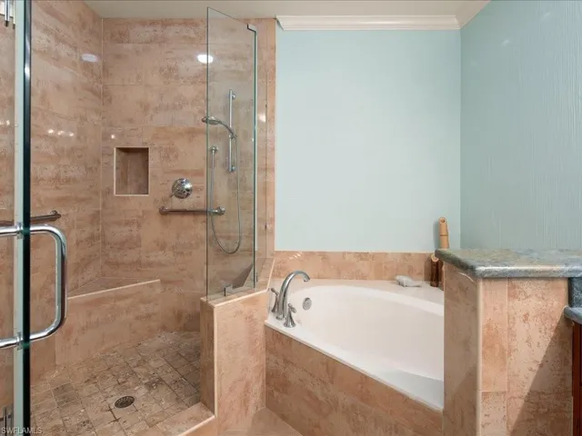Bathroom with crown molding and independent shower and bath
