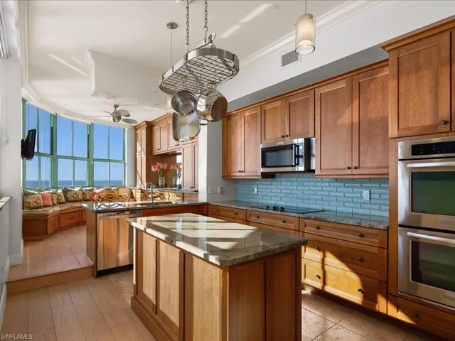 Kitchen with a kitchen island, pendant lighting, tasteful backsplash, ornamental molding, and stainless steel appliances