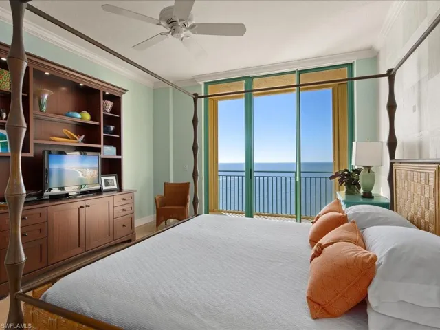 Carpeted bedroom with ornamental molding, a water view, access to outside, and a wall of windows