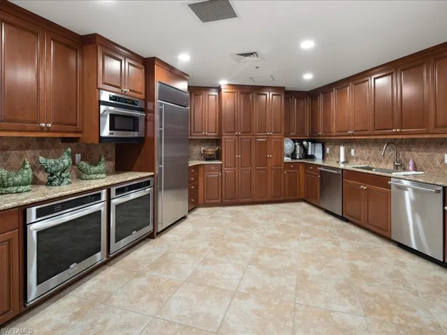 Social room kitchen stainless steel finishes, sink, backsplash, and light stone counters
