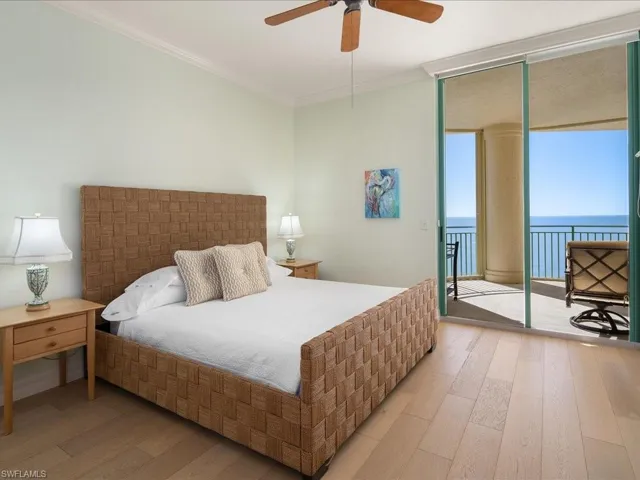 Bedroom featuring crown molding, access to exterior, floor to ceiling windows, a water view, and light hardwood / wood-style floors