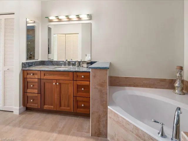 Bathroom featuring tile patterned floors, vanity, and tiled bath