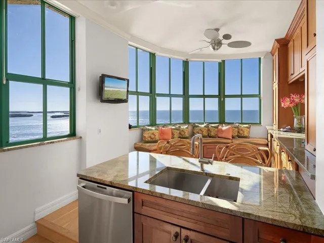 Kitchen with dishwasher, light stone countertops, sink, and ceiling fan