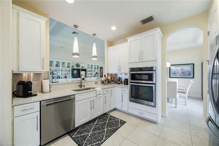 Kitchen with white cabinetry, appliances with stainless steel finishes, hanging light fixtures, light stone counters, and recessed lighting