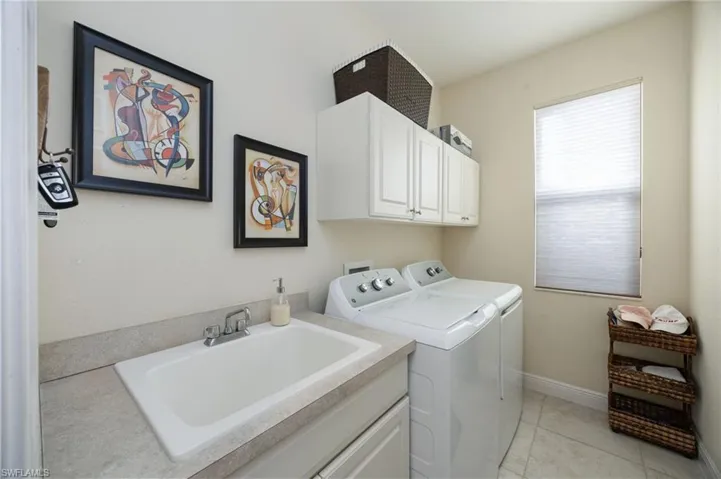 Laundry area with washing machine and clothes dryer, cabinet space, and light tile patterned flooring