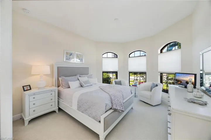 Bedroom with light colored carpet and multiple windows