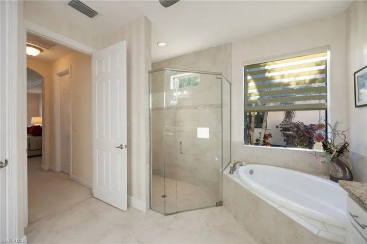 Ensuite bathroom featuring a garden tub, a stall shower, light tile patterned flooring, recessed lighting, and vanity
