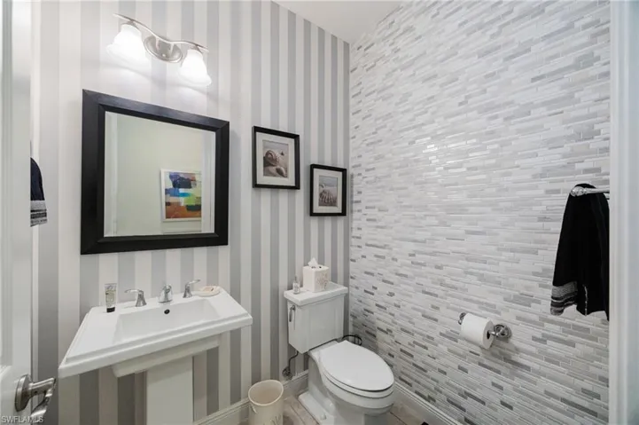 Bathroom featuring wallpapered walls and toilet