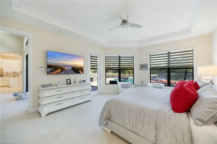 Carpeted bedroom featuring a tray ceiling, access to exterior, and a ceiling fan